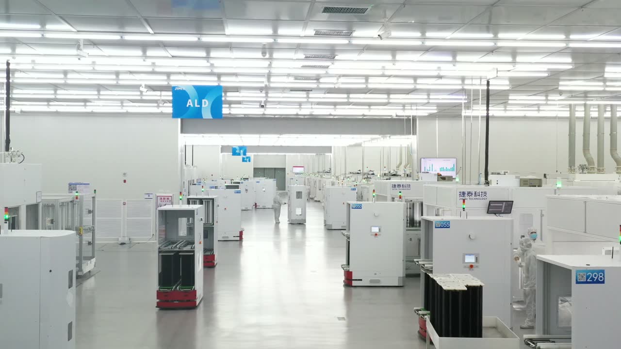 Engineers monitoring semiconductor manufacturing equipment in a cleanroom production facility